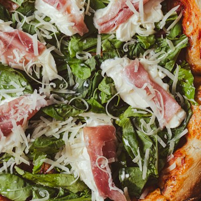 Pizza topped with prosciutto and arugula